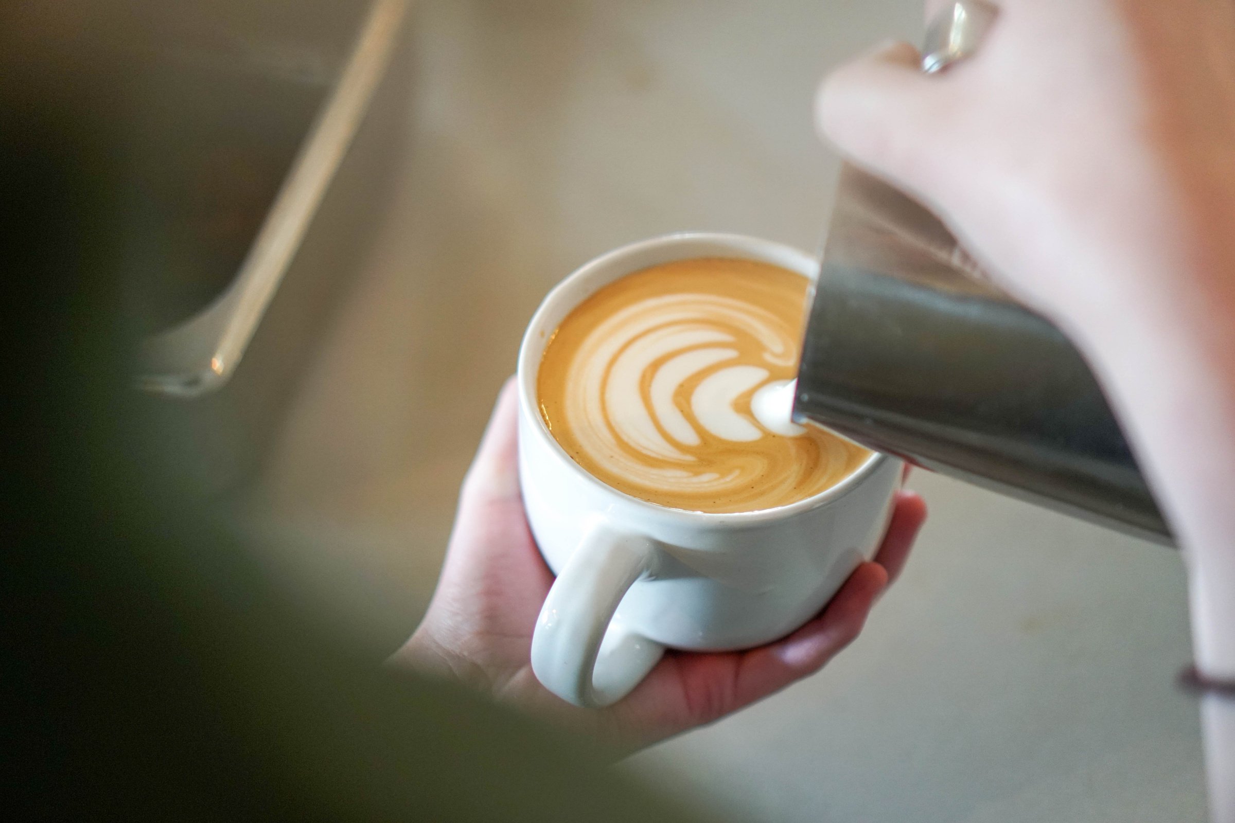 a person is pouring a latte into a cup